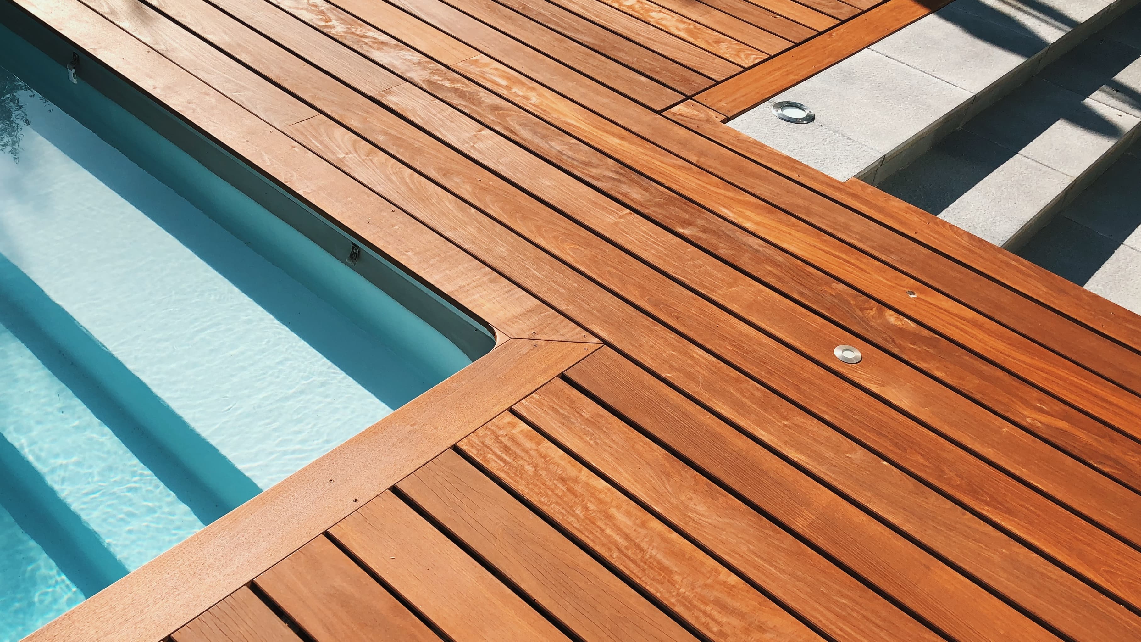 Terrasse extérieure élégante au bord d'une piscine avec des marches en béton symétriques menant à l'eau